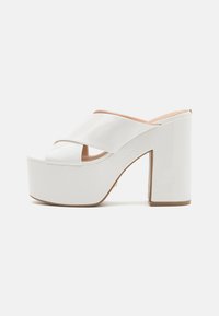 Scarpe con piattaforma in pelle sintetica bianca, dotate di un tacco a blocco spesso, con fasce incrociate nella parte anteriore e una finitura liscia e lucida.