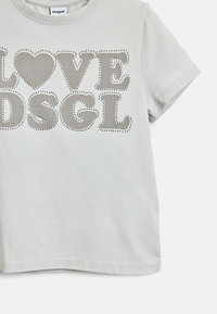 Világosszürke pamut póló, amelyen nagy perforált betűk hirdetik a "LOVE DSGL" feliratot egy szív mintázattal. Rövid ujjú és laza szabású.