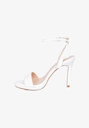 Sandalo bianco con tacco alto a spillo, cinturino alla caviglia e punta aperta, mostrato di lato su uno sfondo bianco.