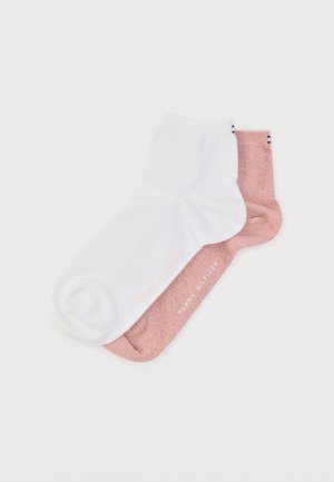 Weiße und hellrosa Knöchelsocken mit weicher Textur; beide Socken sind mit dezenten rosa Schriftzügen gebrandet.