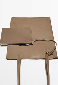 Borsa a spalla in pelle beige con due lunghe tracolle e una clutch coordinata. Texture liscia con cuciture bianche a contrasto e accessori in argento.