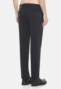 Pantaloni blu navy con taglio dritto, realizzati in tessuto strutturato, dotati di due tasche posteriori e passanti per cintura. Abbinati a scarpe nere.