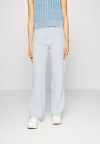 Calças largas em tricot fofas e azuis claras com uma textura suave, combinadas com uma blusa sem mangas em azul claro.