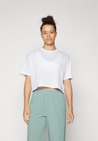Maglietta bianca a taglio corto realizzata in tessuto morbido, con scollatura rotonda e maniche corte, abbinata a pantaloni verde chiaro con cintura elastica.