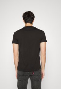 Camiseta negra de manga corta en un color sólido, hecha de algodón, con cuello redondo y un diseño limpio y minimalista.