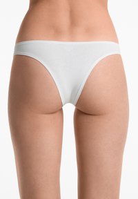 Witte katoenen thong met een gladde textuur, lage tailleband en minimale bedekking. Ontworpen voor comfort en een naadloze pasvorm.