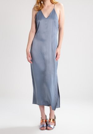 Grå satin midi-kjole med V-udskæring og tynde stropper, med en sideslids. Parret med metalliske blokhæle sandaler.
