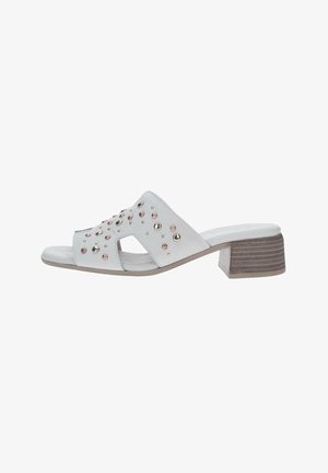 Le sandali bianchi con tacco a blocco presentano un design tagliato, adornato con borchie metalliche rosa e argento, con un tacco beige testurizzato.