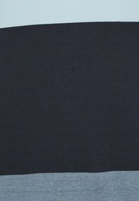 Sections horizontales de tissu en bleu clair, bleu marine foncé et gris clair texturé, montrant un contraste de couleur et de texture.