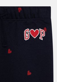 Mornarsko modri hlače z vezenim logotipom "G♥P" in razpršenimi majhnimi rdečimi srčki. Mehka tkanina z elastičnim pasom; sproščen dizajn.