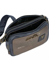 Braune und marineblaue Leder-Crossbody-Tasche mit mehreren Reißverschlussfächern, dekorativer Steppnaht und einem strukturierten Paneel mit dem Markennamen.