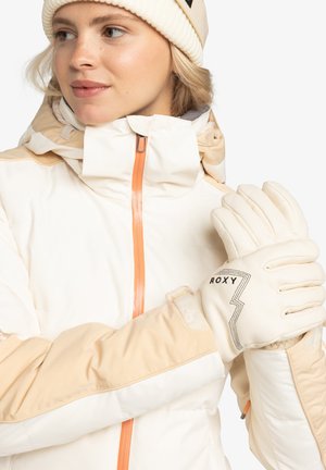Witte en beige winterjas met een oranje rits, gecombineerd met crèmekleurige handschoenen met een zwart "Roxy"-logo en gestructureerde details.