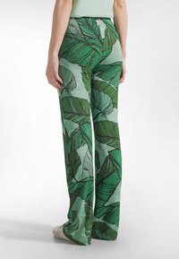 Grüne, weit geschnittene Hosen mit einem Blattmuster in verschiedenen Grüntönen. Hergestellt aus einem leichten Stoff mit glatter Textur.