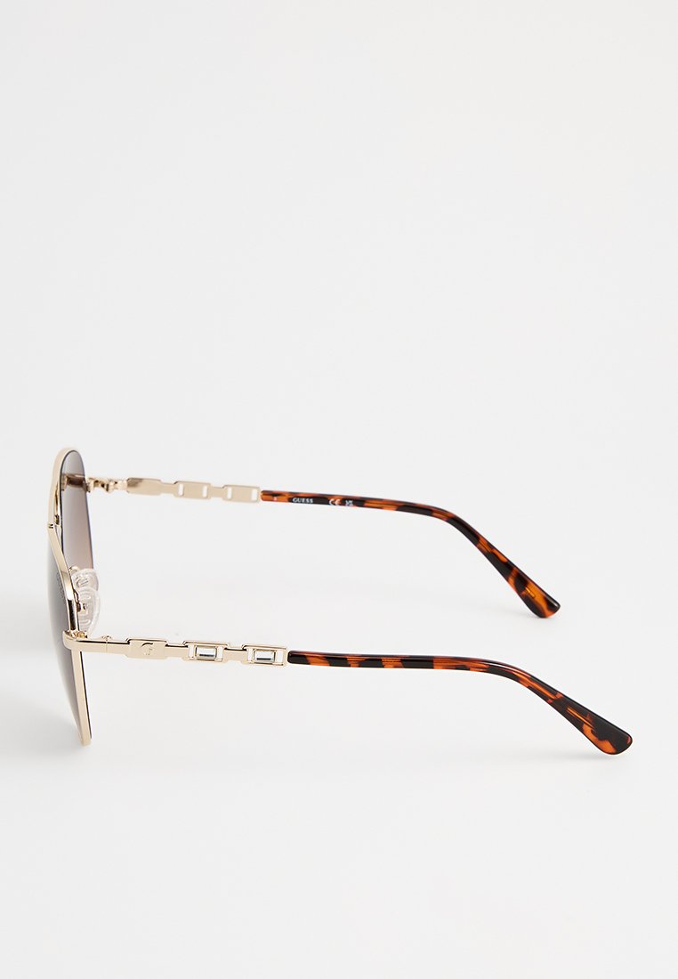 Occhiali da sole con una montatura in oro metallizzato e lenti scure. Le stanghette presentano un motivo tartarugato, decorate con accenti rettangolari.