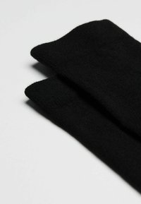 Sorte sokker stablet sammen, lavet af et blødt tekstil. De har en glat overflade og ribbede manchetter, med et enkelt design.