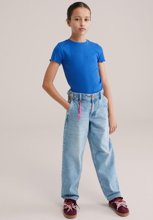 Sinine soonikkoes lühikeste varrukatega särk, kõrge vöökohaga helepesuga teksapüksid, roosa paelaga detail ning burgundiapunased tossud mustriga paeltega.