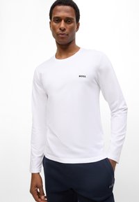 White long-sleeve T-shirt made of cotton with a round neckline, featuring a small black "BOSS" logo on the chest.