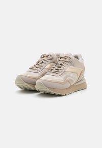 Zapatillas beige que presentan una mezcla de materiales de ante y malla, un diseño estratificado, cuello acolchado y una suela de goma texturizada.