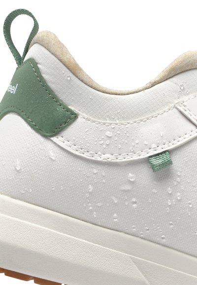 Basket blanche avec une texture mate, accent en cuir vert et gouttes d'eau. Comprend un onglet au talon et une doublure intérieure crème.