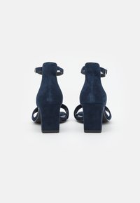 Mörkblå mocka högklackade sandaler med ankelsnoddar och öppen tå-design. Kraftig klack och slät textur, med justerbar spänne.