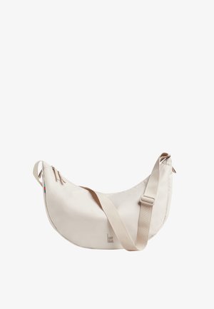 Sac d'épaule beige en forme de croissant avec une sangle ajustable, une fermeture éclair et un petit logo "GOT BAG" au centre en bas sur le devant.