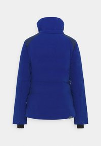 Doudoune bleue avec col montant, poignets élastiques et accents bleu foncé sur les épaules ; texture lisse et isolante.