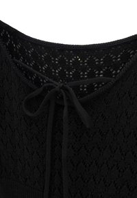 Tissu tricoté noir avec un motif en dentelle comprenant un nœud noué au niveau de l'encolure, montrant la texture et les détails du tissage ouvert.