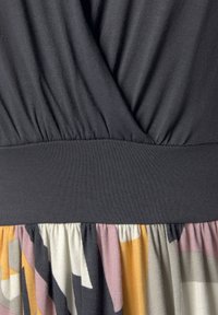 Abito con un top grigio scuro caratterizzato da tessuto arricciato e una vita texturizzata, che si trasforma in una gonna a motivo e multicolore.