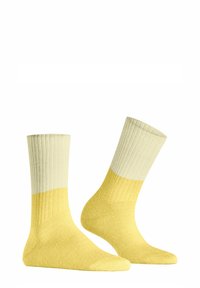 Gelbe Socken mit einem strukturierten Rippdesign, das einen Farbverlauf von hellem Gelb zu dunklerem Gelb aufweist, und einem weichen, mittelschweren Strick.