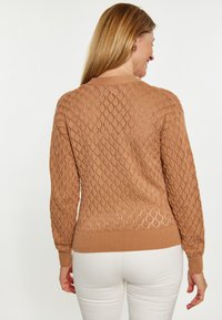 Maglione marrone lavorato a maglia con motivo a rombi, colletto rotondo, maniche lunghe e orlo a costine. Materiale leggero e a trama aperta.