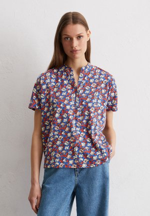 Floral kurzärmlige Bluse in Blau mit einem roten und cremefarbenen Muster, Stehkragen und Knopfdetail am Rundhalsausschnitt.