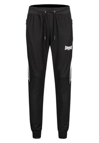 Fekete sportos melegítőnadrág fehér oldalsávokkal, rugalmas derékrésszel és húzózsinórral, jobb combján "Lonsdale London" felirattal, cipzáras zsebekkel.