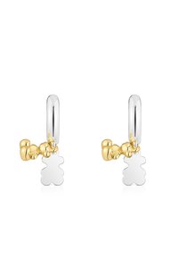 Srebrne kolczyki koła z błyszczącym żółtym złotym zawieszką w kształcie misia oraz gładką srebrną sylwetką misia wiszącą na każdym kolczyku.