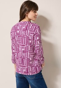 Lilac- ja valkoisilla geometrisilla kuoseilla varustettu kolmannes hiha -paita, jossa on pyöreä kaula-aukko ja rento istuvuus. Rentoa tyyliä pehmeästä kankaasta.