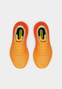 Φωτεινά πορτοκαλί παπούτσια για τρέξιμο Saucony με κίτρινα στοιχεία, λευκές σόλες και πράσινες εσωτερικές σόλες με την ένδειξη «Neutral», σε θέα από πάνω σε λευκό φόντο.