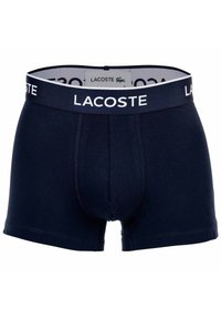 Mörkblå bomullsboxershorts med en vit Lacoste-logotyp på midjebandet. Har en tajt passform och mjuk textur.