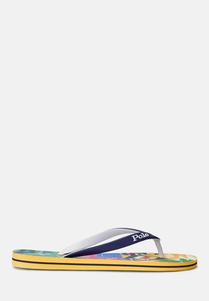 Varvastossu, jossa keltainen pohja, värikäs trooppinen kuvio pohjallisosassa ja laivastonsininen remmi, jossa lukee "Polo", valkoisella taustalla.