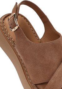 Sandali con zeppa in suede marrone con cinturino slingback, caratterizzati da una fibbia metallica e cuciture visibili sulla zeppa e sulla parte superiore.