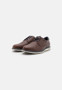 Brown textured leather shoes with rounded toe, contrasting white stitching, and a slightly elevated sole. Black accents at the heel.