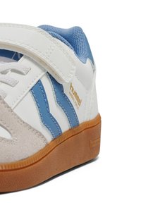 Biało-niebieski sneaker Hummel z zamszowym noskiem, paskiem na rzep, wyściełanym kołnierzem i gumową podeszwą.