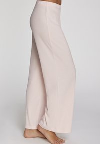 Lichtroze, geribde wijde pijpen met een elastische tailleband, een gladde textuur en een relaxte pasvorm, die net boven de enkel reiken.