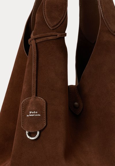 Καφέ τσάντα από σουέτ Polo by Ralph Lauren με ραμμένη ταμπέλα και λεπτομέρεια από ασημένιο δαχτυλίδι σε ουδέτερο φόντο.