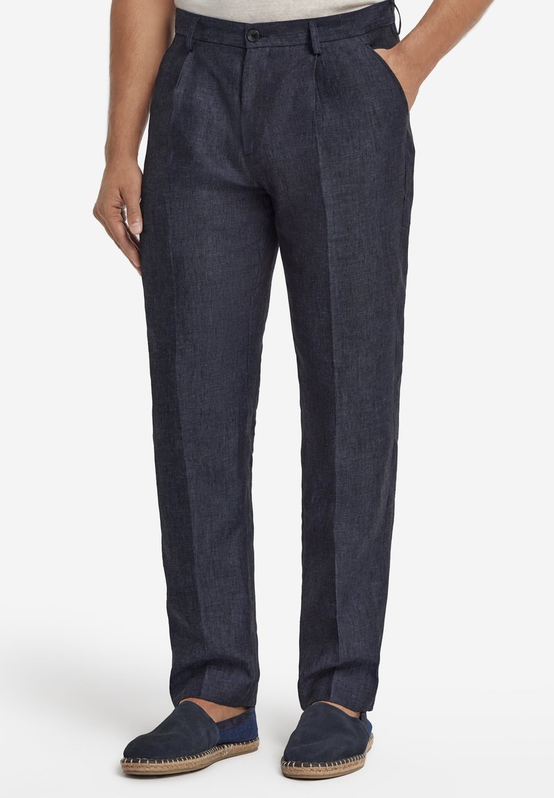 Marinblå linnebyxor med strukturerad yta, utrustade med framåtvikt, sidfickor och kombinerade med marinblå slip-on skor.