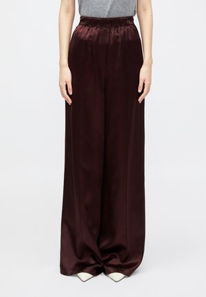 Pantalons larges bordeaux en satin avec une taille élastique, présentant des coutures verticales et une texture lisse et brillante.