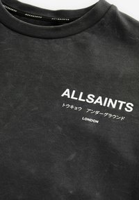 Černé bavlněné tričko s kulatým výstřihem a opotřebenou texturou, s bílým potiskem: "ALLSAINTS," japonské znaky a "LONDON."