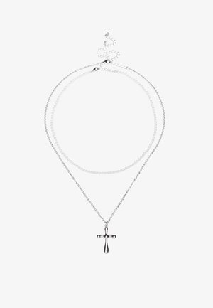Colar prateado de duas camadas com um simples pendente de cruz. As correntes têm texturas diferentes; uma é lisa, a outra é em contas.