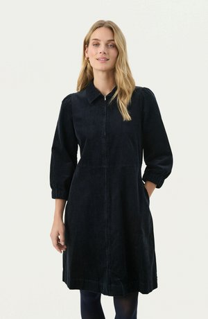 Donkerblauwe corduroy jurk met een kraag, frontale rits en pofmouwen. Beschikt over zijzakken en een knielange zoom.