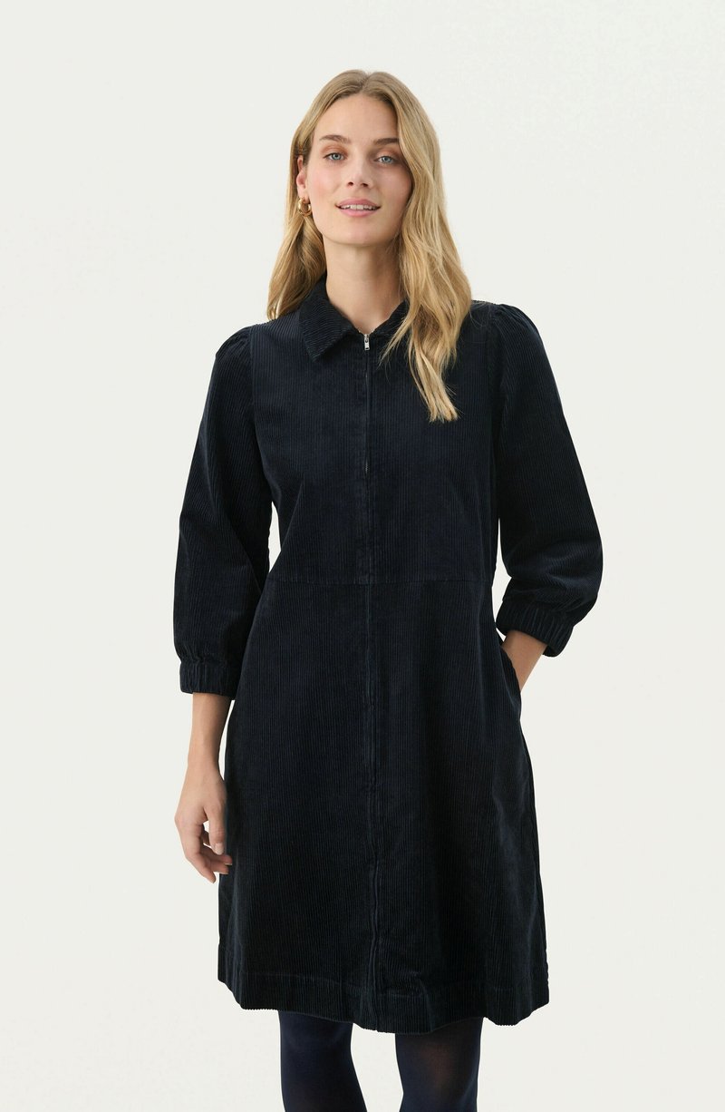 Vestito in corduroy blu scuro con colletto, zip frontale e maniche a sbuffo. Presenta tasche laterali e orlo fino al ginocchio.
