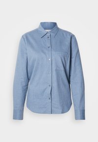 Chemise bleu clair à manches longues avec boutons, col et poche poitrine, présentée sur fond blanc.