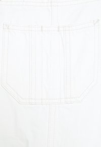 Bílé džínové plátno s zadní kapsou, která má dvojité horní prošití, obdélníkový tvar a mírně texturovaný povrch.